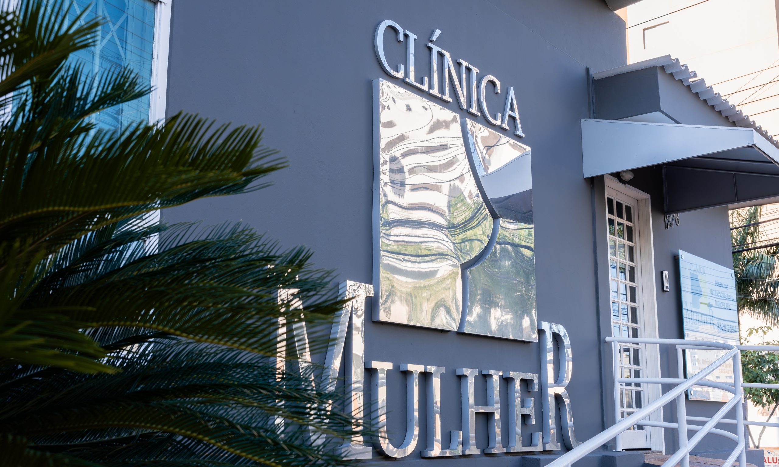 Fachada moderna da Clínica Mulher com logo em letras grandes